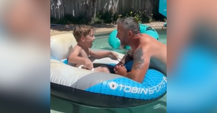 Chris Overton talks to his step-son, Jameson, in a pool. Jameson looks shocked.