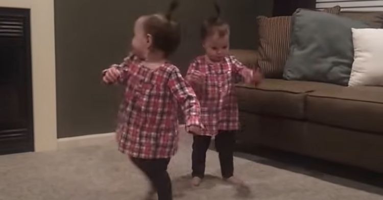 Twin toddlers dance to dad's music on the guitar.