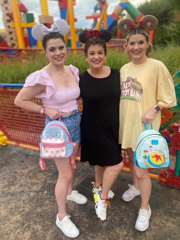 Jane Treacy smiles and poses at Disney with her adult daughters. All of them are wearing Mickey ears.