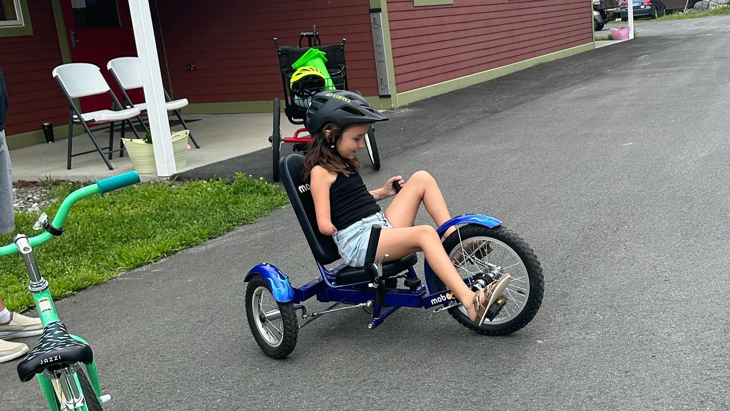 child with limb difference is seen riding tricycle.
