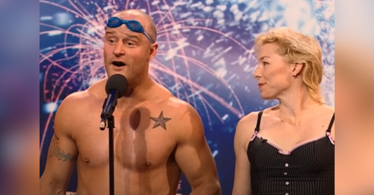 a man with goggles stands on the bgt stage as his assistant looks on