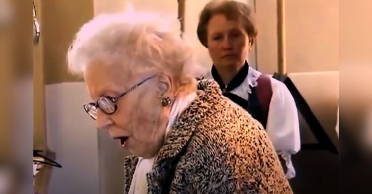 Magda Olivera singing at 96 years of age. Image shows Magda reading from music in her had as another woman stands in the background watching.