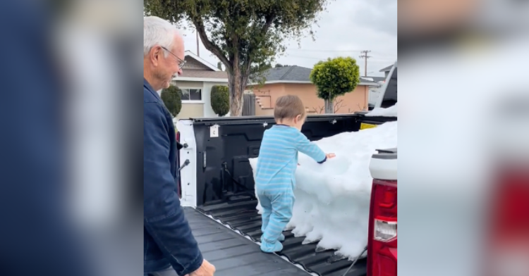 little boy touches snow in truck