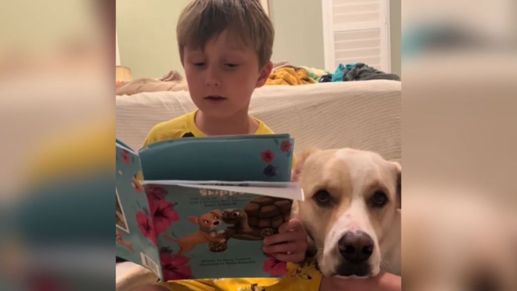 A little boy with dyslexia reads out loud to his dog.