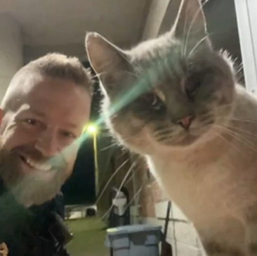 A police officer and a cat staring into the camera together. 