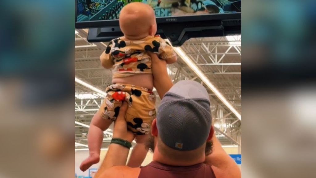 A dad holds up his baby inside a store.