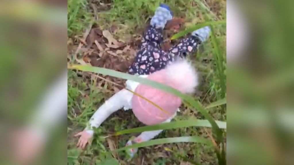 A little girl laying in the grass after falling down.