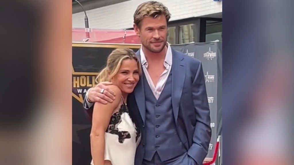Chris Hemsworth smiles with an arm around wife Elsa Pataky, who is also smiling.