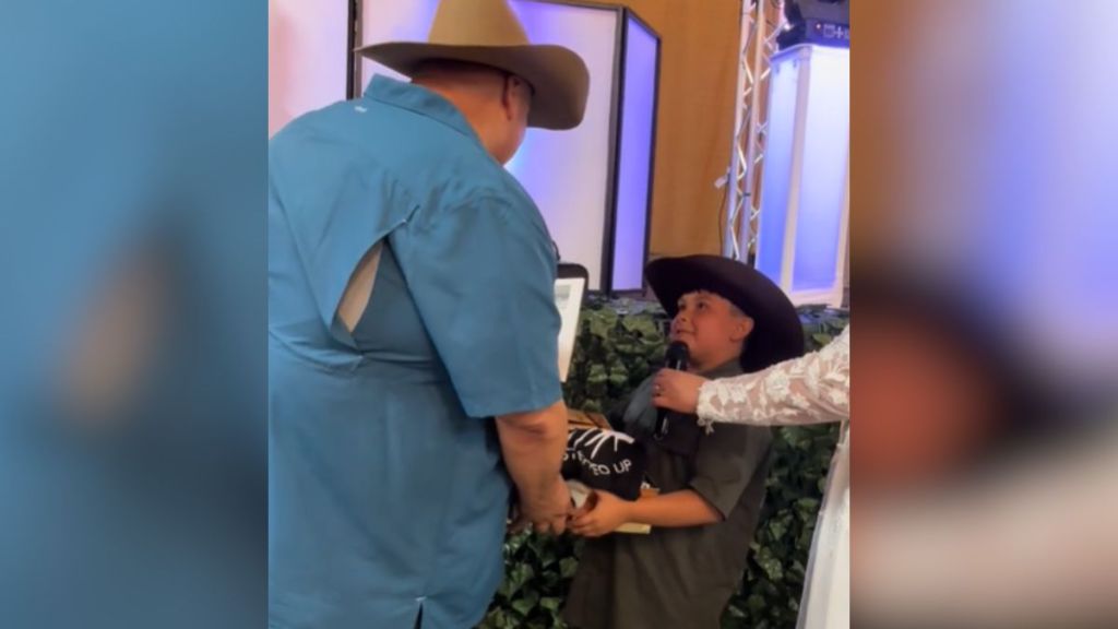 A little boy in a cowboy hat presenting a gift to his new dad.