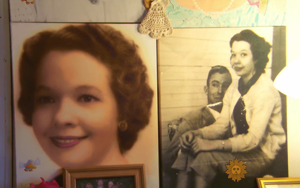 Two photos hang on a wall. One is of a young woman, smiling. The other shows Carolyn smiling as she sits in Clarence's lap.