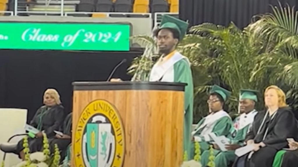 A valedictorian in graduation robes giving a speech.