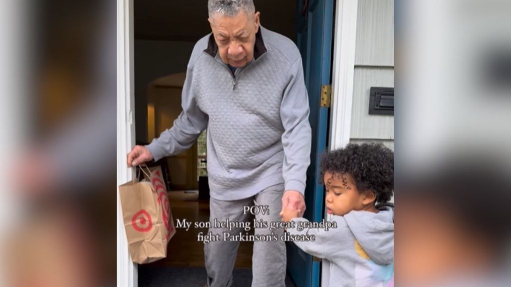 A little boy helping his great-grandpa walk out the front door.