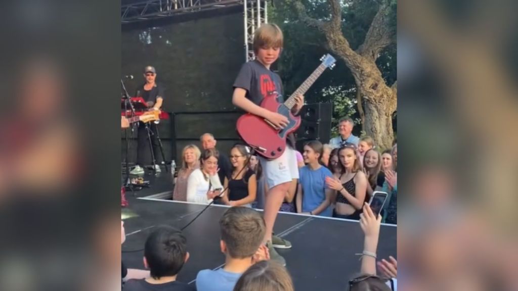 A young boy performing on stage with a guitar.