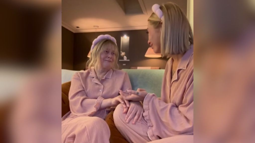 A mom and daughter wearing pink pajamas sharing an emotional moment.