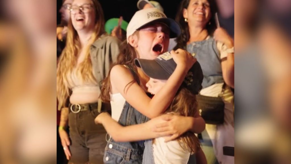 Two little girls crying and hugging each other at a concert.