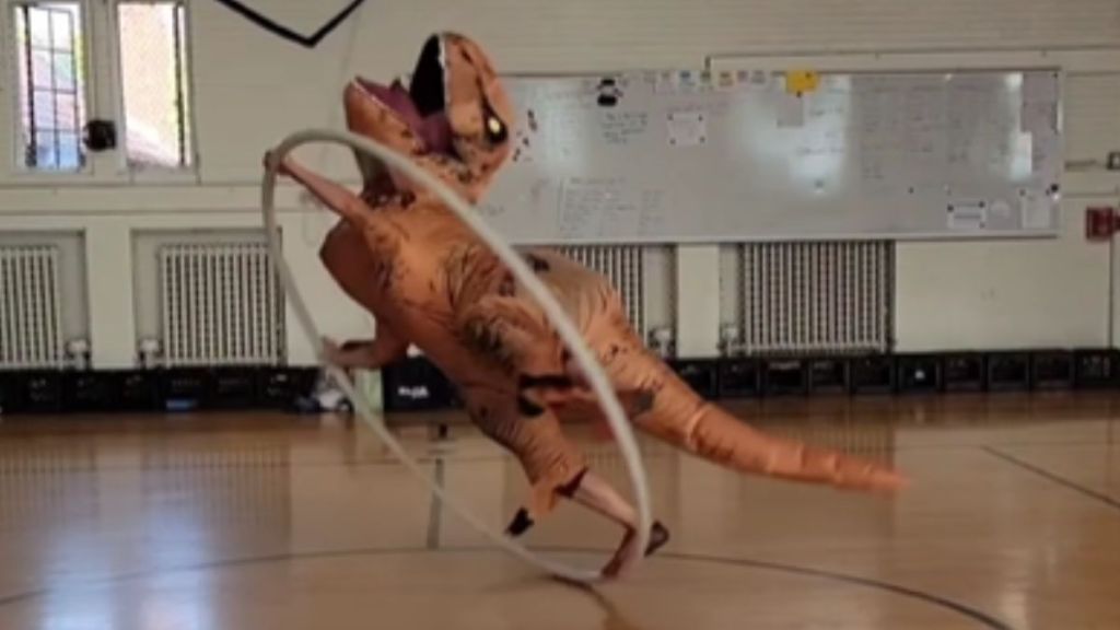 A person in a T. rex costume dancing with a hoop.