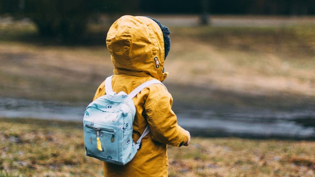 A little boy wearing a raincoat outdoors.