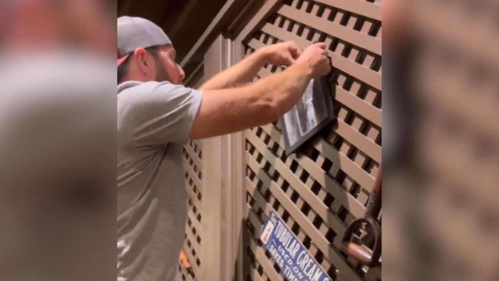 A man hanging a photo on the wall at Cracker Barrel.