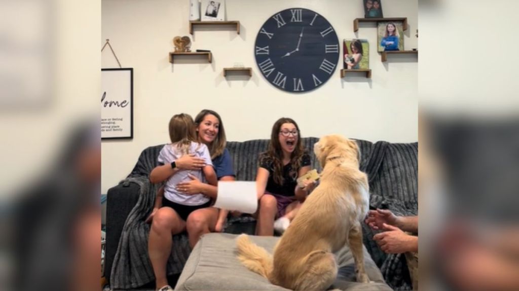 A happy family on the couch with a golden retriever.