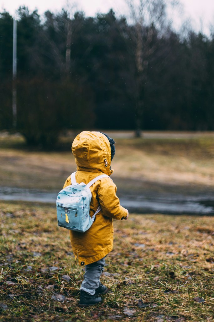 A little boy wearing a raincoat outdoors.