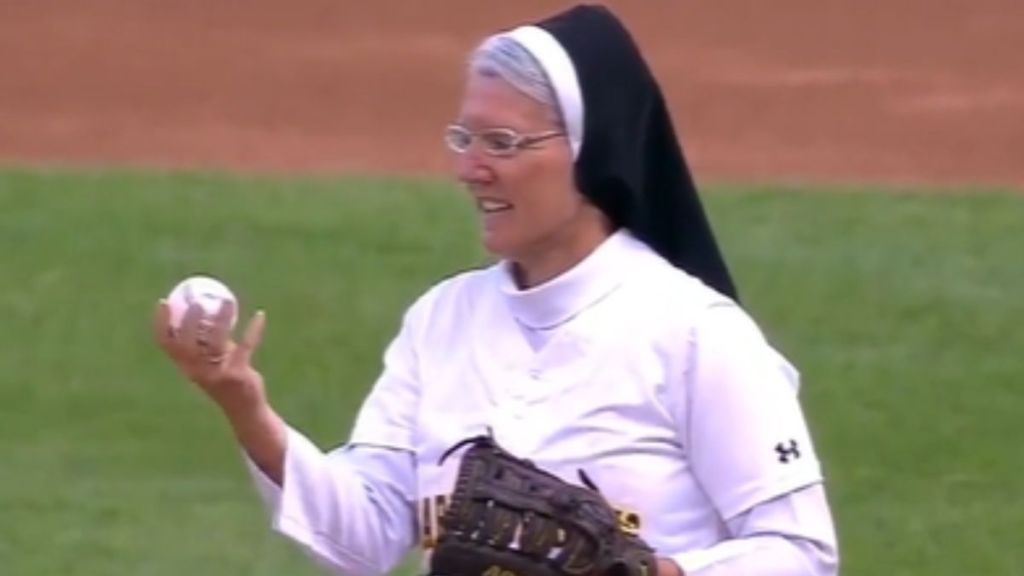 A nun holding a baseball and wearing a catcher's mitt.