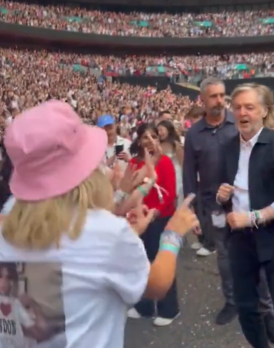 Paul McCartney dances in the crowd at a concert.