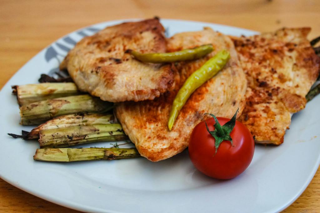 Close up of cooked chicken filets adorned with veggies