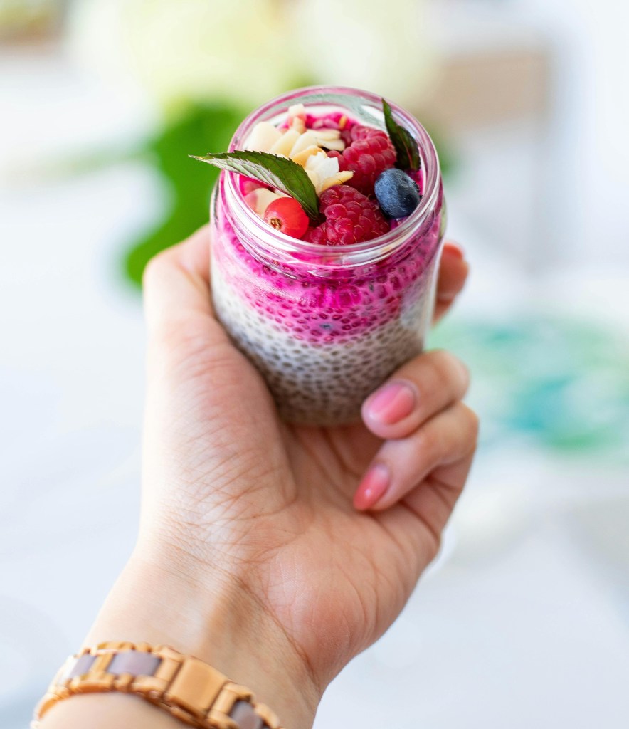 Someone holds a small class of a fruity treat with chia seeds