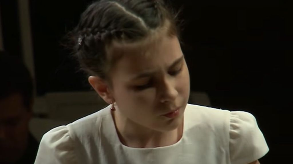 A young girl concentrating while she plays piano.