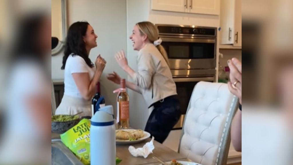 Two women looking very excited as they share news with each other.