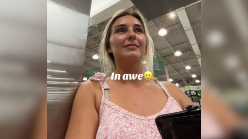 A blonde woman in a pink shirt looking happy.