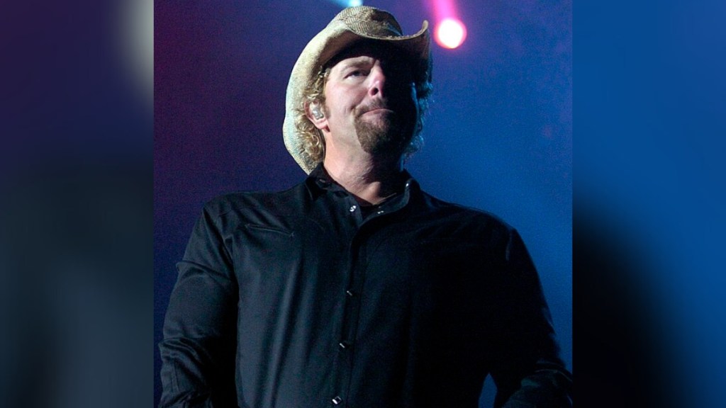 Toby Keith looks out in the distance while on stage. He has a serious look on his face