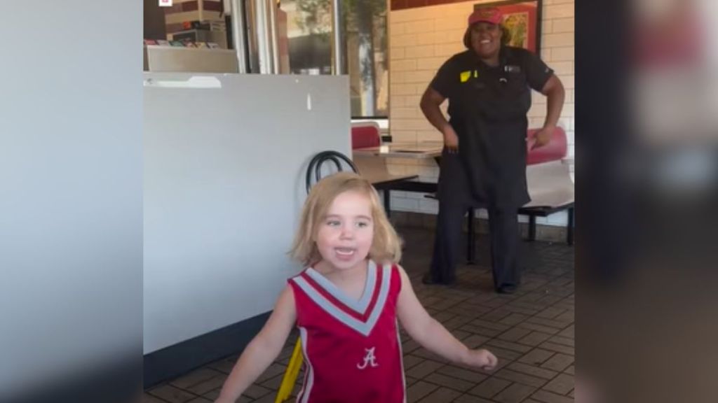 A little girl singing and dancing with a Waffle House employee.