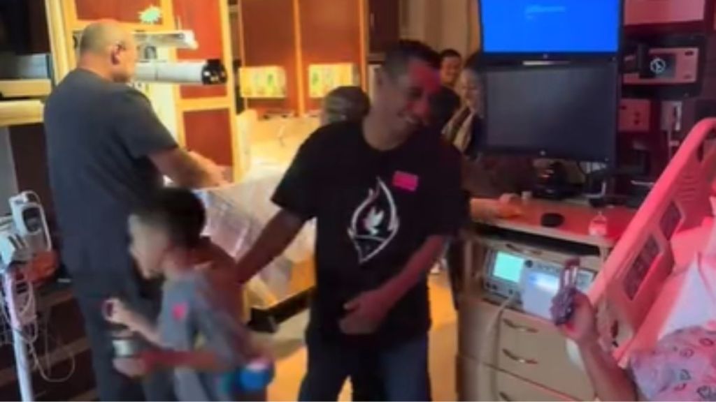 A man standing in a hospital room with his family.