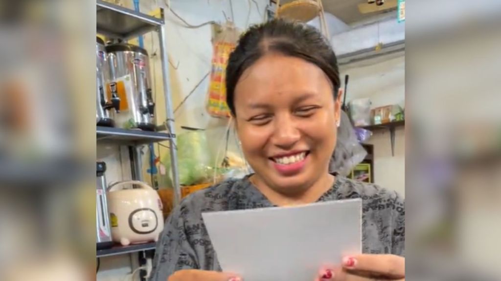 A woman looking at a piece of paper and smiling.