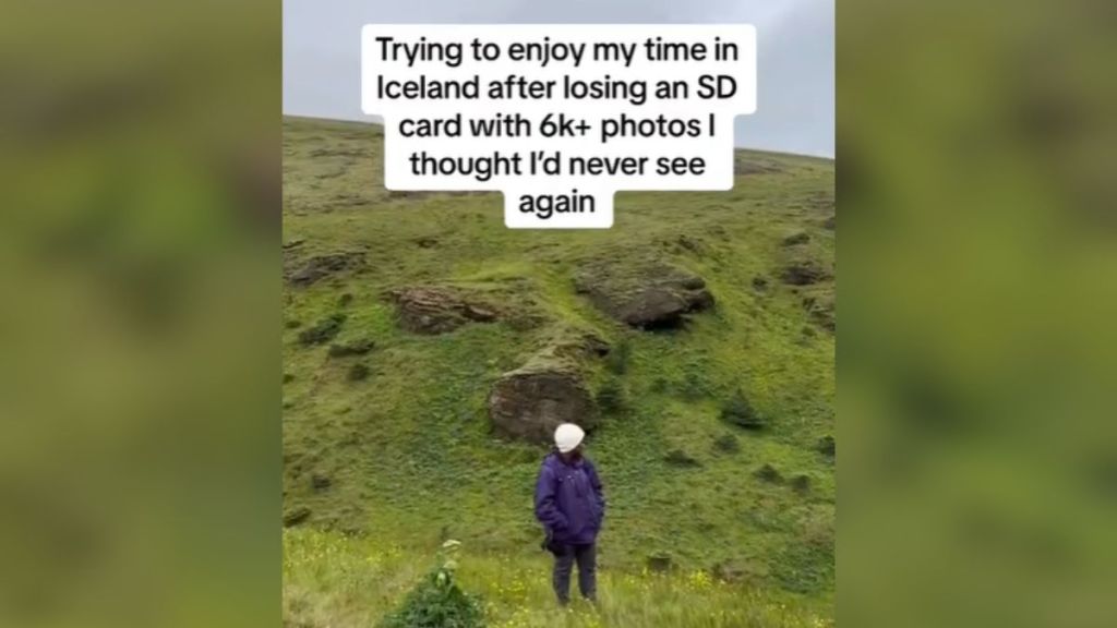 A photographer standing on a grassy hill outdoors.