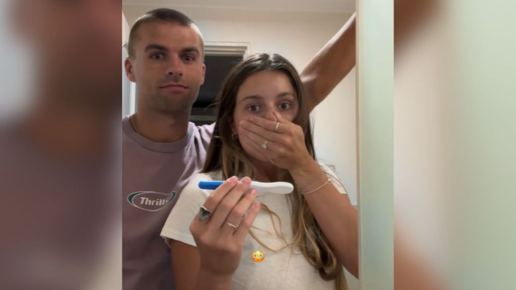 A woman and her husband look shocked at the results of a pregnancy test.