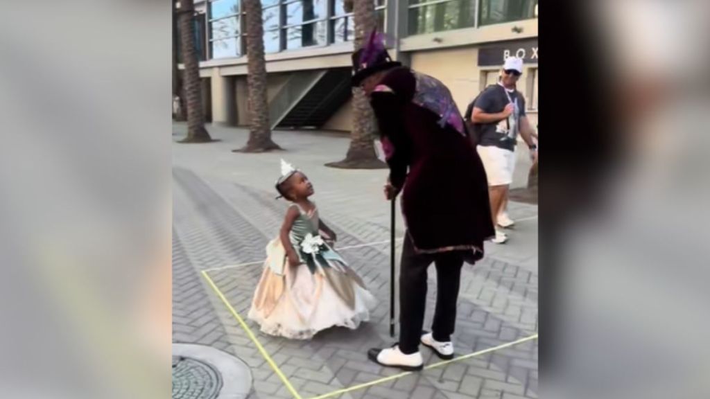 A little girl dressed as Princess Tiana meets a Dr. Facilier cosplayer.