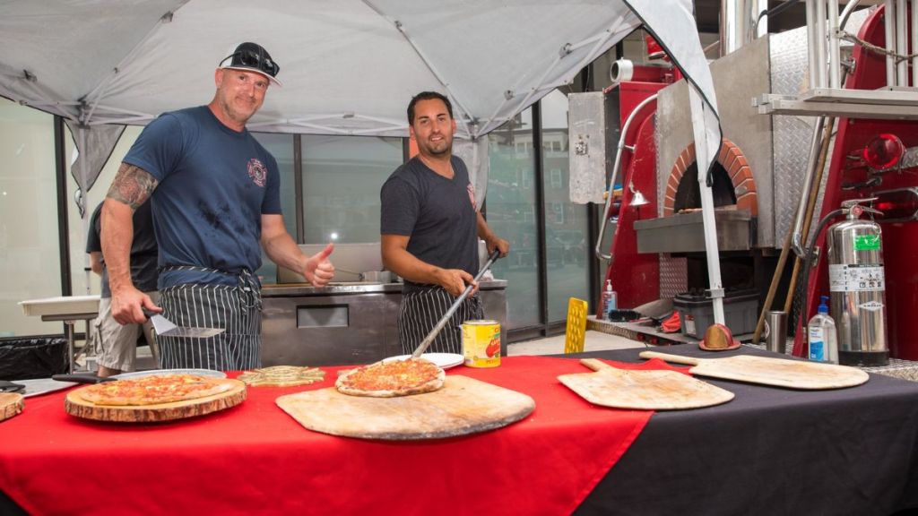 Image shows staff for 3rd Alarm Pizza catering an event with their fire truck pizza oven at Gibson Sotheby's International Realty.