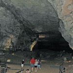 Image shows a main cavern inside Mammoth Cave National Park with tourists walking around.