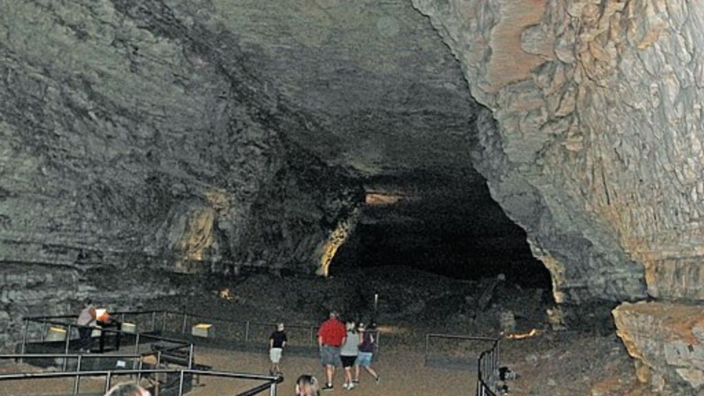 Image shows a main cavern inside Mammoth Cave National Park with tourists walking around.