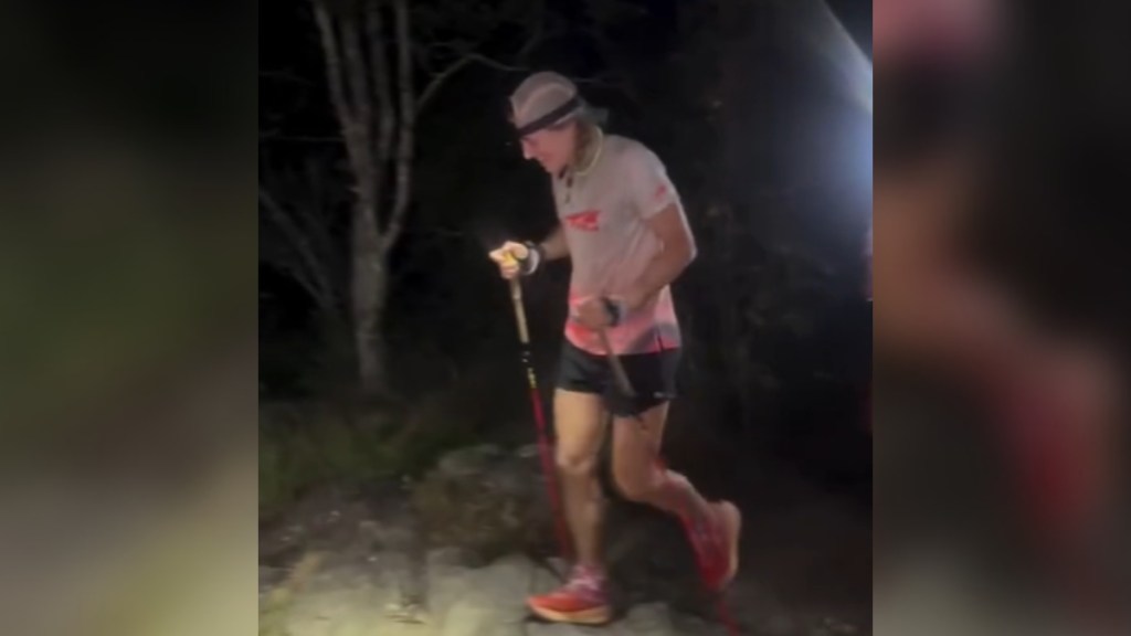 A woman smiles as she hikes in the dark.