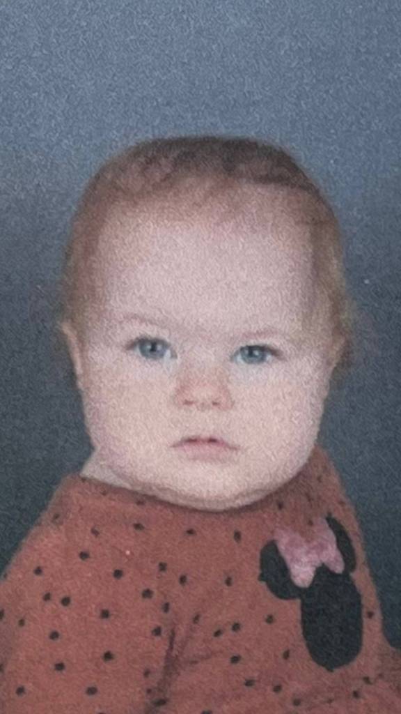 Close up of a baby for picture day. She has one eyebrow raised and a pretty blank look in her eyes.