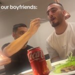 A man reaches over to feed the man sitting next to him, using chop sticks. The second man's mouth is open, ready for the food. Text on the image reads, "Our boyfriends:"