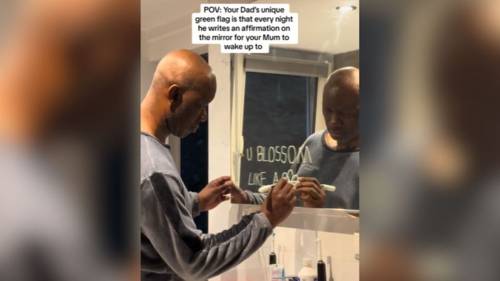 A man writing a message on a mirror in the bathroom.