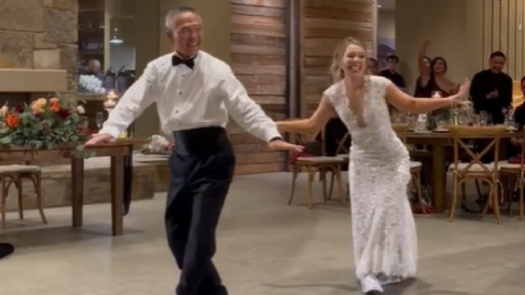 A father and daughter hold out their arms as they dance at the woman's wedding. They're both smiling wide