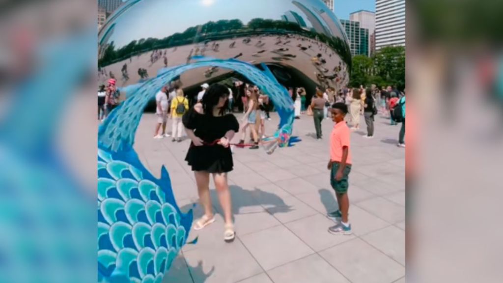 A woman in black performing flow art with a dragon poi.