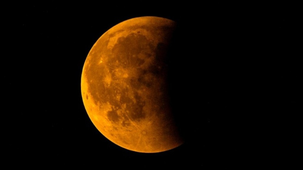 Close up of a partial eclipse. The moon has a reddish-brown tint.