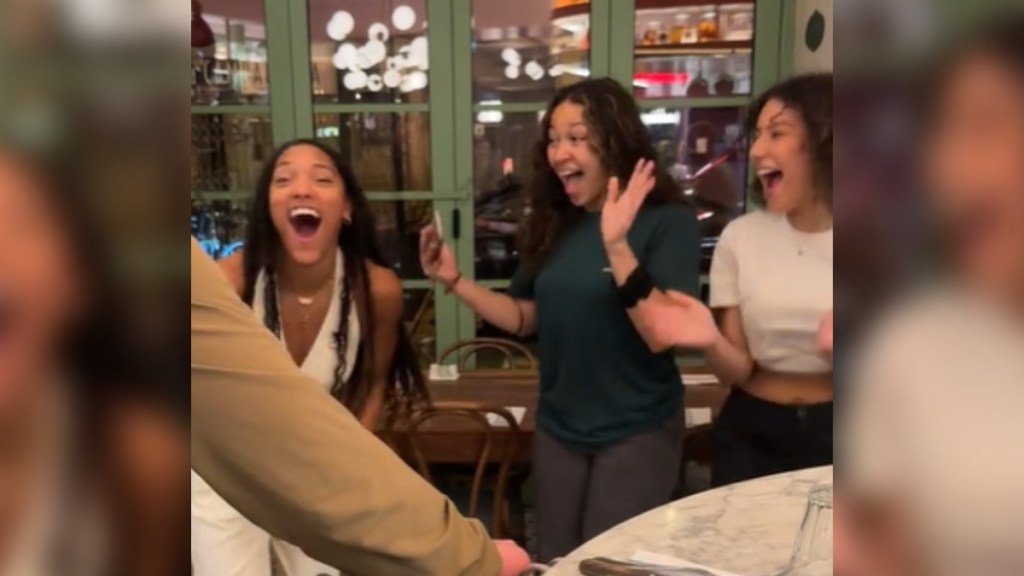 Tara Davis-Woodhall happily screams with two fans. All three of them have them mouths open wide as they react to something exciting