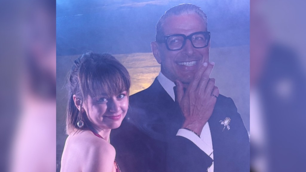 A young woman smiles as she poses with a Jeff Goldblum cutout